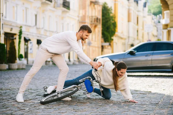 Мужчина помогает женщине с велосипедом забраться на улицу — стоковое фото