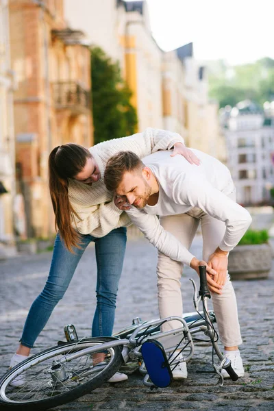 Hombre infeliz cerca de bicicleta sosteniendo la rodilla y la mujer —  Fotos de Stock