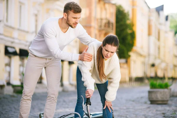 Чоловік заспокоює жінку, поранену від падіння з велосипедом — стокове фото