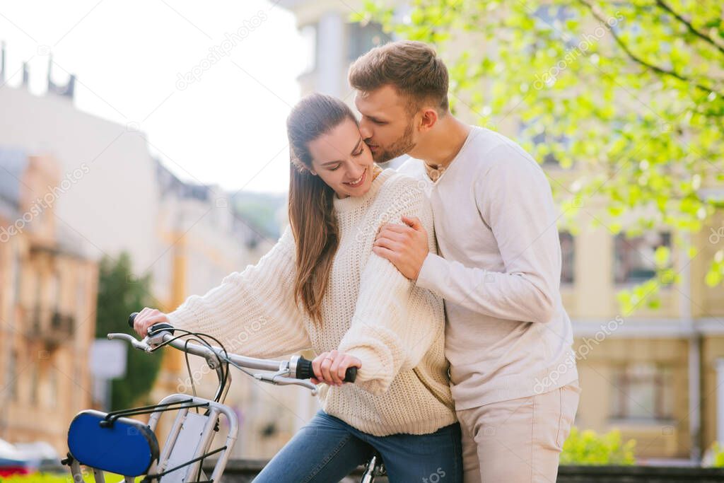 Woman on bicycle and a kissing man standing nearby