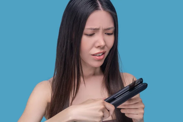 Long-haired woman having troubles while straightening her hair — Stock Photo, Image