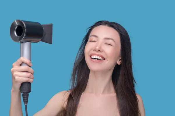 Усміхнена жінка висушує волосся з новою фен — стокове фото