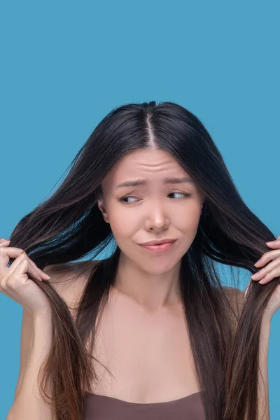 Young beautiful woman looking at her long hair — Stock Photo, Image