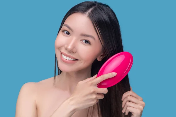 Жінка чистить волосся рожевим пензлем для волосся — стокове фото