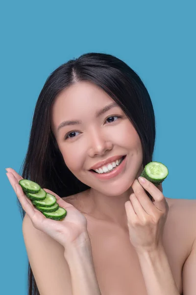Kvinna som använder gurkor för ansiktsmask — Stockfoto