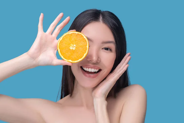 Sorrindo jovem mulher segurando metade de laranja — Fotografia de Stock