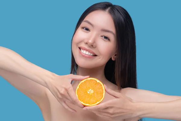 Leende ung kvinna som håller citrus i sina händer — Stockfoto