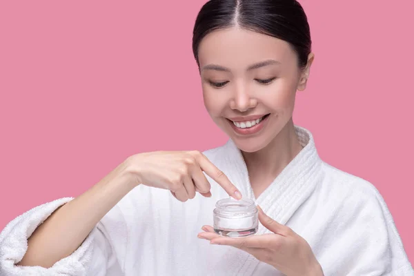 Smiling young woman trying new cosmeological cream