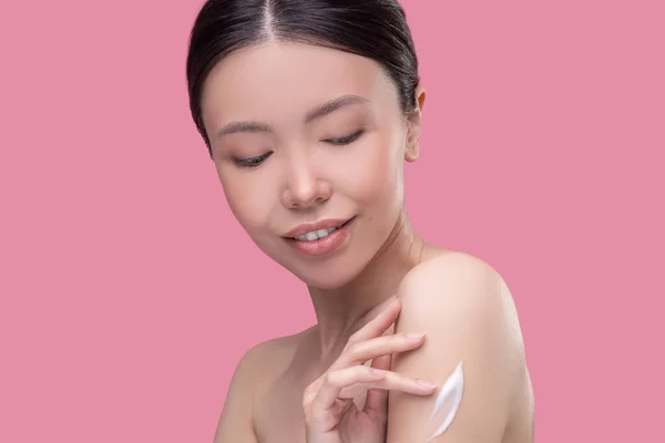 Giovane donna utilizzando nuova crema corpo nutriente — Foto Stock