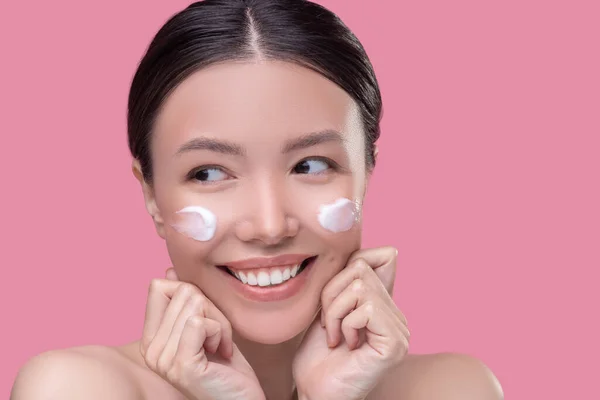 Smiling woman having face cream on her cheekbones — Stock Photo, Image