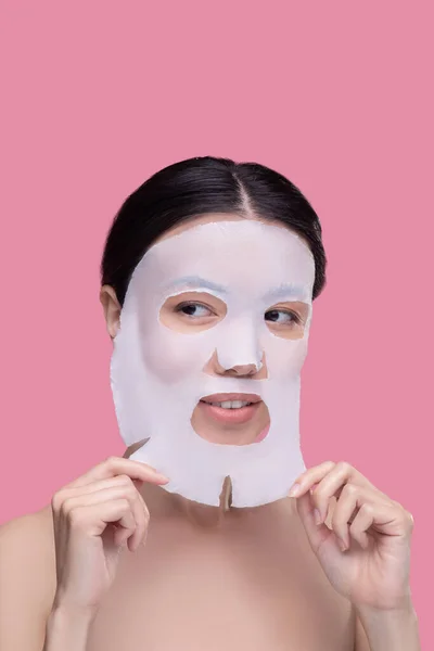 Young woman taking off cosmetological face mask — Stock Photo, Image