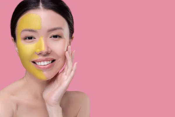 Woman having a facial mask on half of her face — Stock Photo, Image