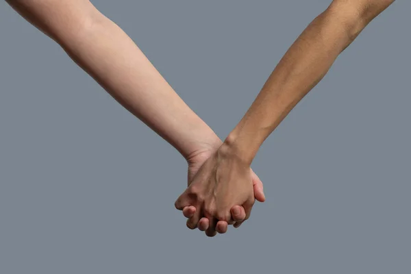 Close-up of light-skinned and dark-skinned people holding hands — Stock Photo, Image