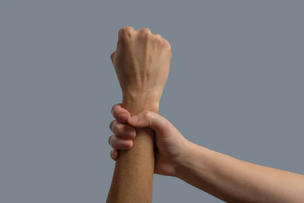 Close-up of light-skinned hand clenching dark-skinned wrist — Stock Photo, Image