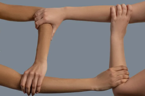 Close-up van vier handen van verschillende rassen vormen vierkant — Stockfoto