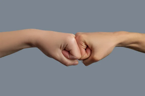 Close-up of light-skinned and dark-skinned fists bumping together — Stock Photo, Image