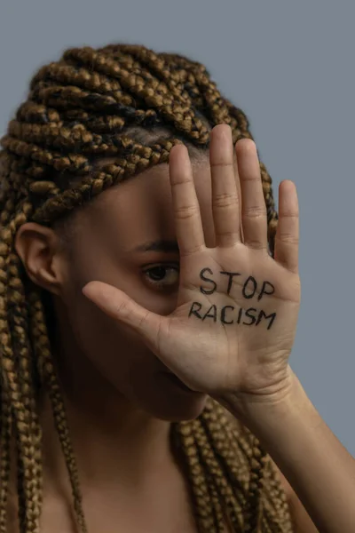 Jovem afro-americano mulher cobrindo seu um olho com palma com parar racismo lettering — Fotografia de Stock