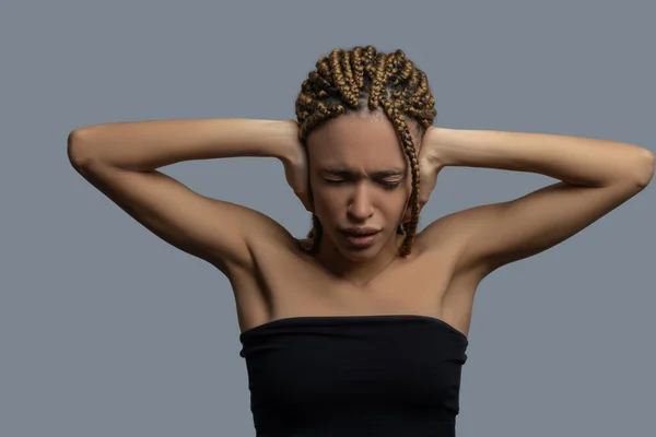 Απογοητευμένη νεαρή Αφρο-Αμερικανίδα που κατσουφιάζει, καλύπτοντας τα αυτιά της με χέρια. — Φωτογραφία Αρχείου