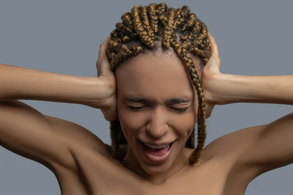 Frustrierte junge Afroamerikanerin runzelt die Stirn, schließt die Ohren mit den Händen und schreit — Stockfoto
