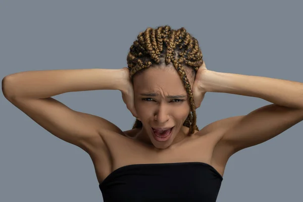 Förkrossade unga afroamerikanska kvinna stänga öronen med händerna, skrikande — Stockfoto