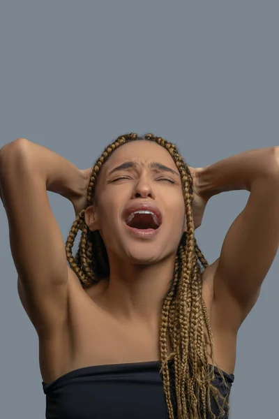 Разочарованная молодая афроамериканка, держащая голову на руках, крича от боли — стоковое фото