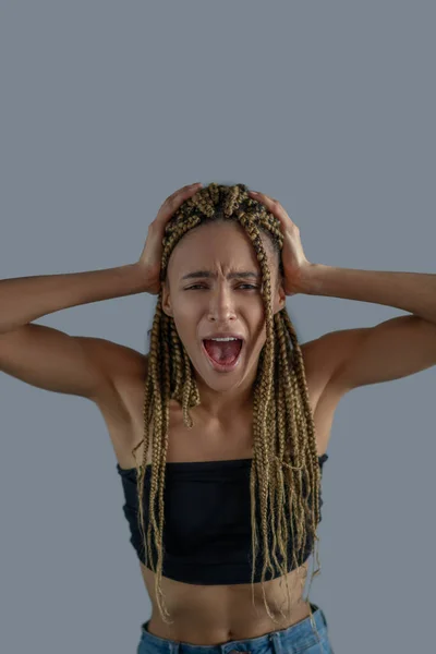 Συντετριμμένη νεαρή Αφρο-Αμερικανίδα κρατώντας το κεφάλι της στα χέρια, ουρλιάζοντας — Φωτογραφία Αρχείου