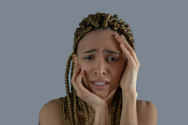 Joven afroamericana devastada sosteniendo su cara con sus manos, frunciendo el ceño con dolor — Foto de Stock