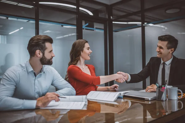 Pareja feliz haciendo un acuerdo con un agente de ventas — Foto de Stock