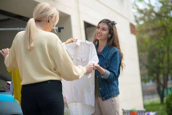 Θετική ωραία γυναίκα που προσφέρει την μπλούζα στον πελάτη — Φωτογραφία Αρχείου