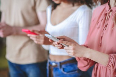 İki kızın ve elinde akıllı telefonlar tutan adamın elleri, yüzü yok.