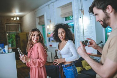 Akıllı telefondan poz veren iki kızın fotoğrafını çeken adam.