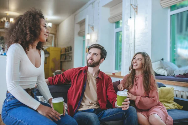女孩和男人看着卷曲的女朋友喝着咖啡沙发 — 图库照片