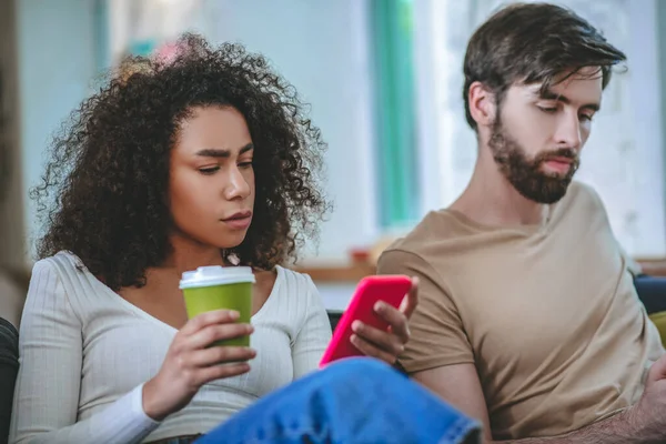 Curly girl with coffee and smartphone and guy