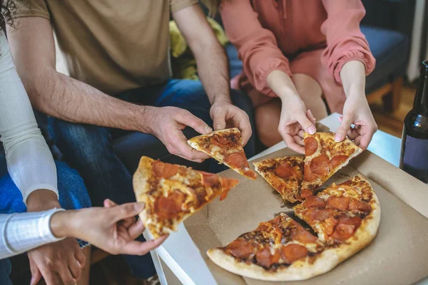 Mãos masculinas e femininas segurando pedaço de pizza sobre caixa — Fotografia de Stock