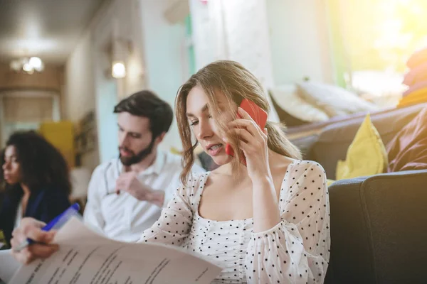 Jovencita hablando en smartphone sosteniendo documentos en la mano — Foto de Stock