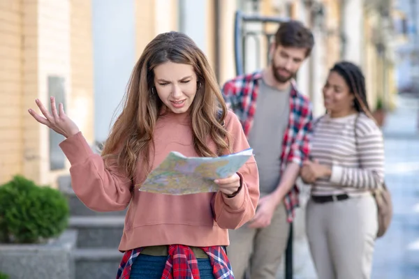 Jong volwassen meisje met een kaart vrienden in de buurt. — Stockfoto