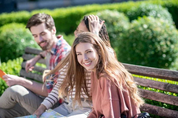 Tre unga vänner på bänken på solig dag — Stockfoto