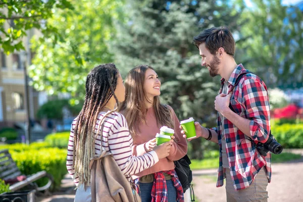 Lång kille och två långhåriga tjejer med kaffe på torget — Stockfoto