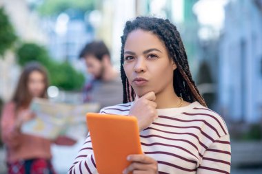 Sokakta duran tabletli düşünceli melez kız.