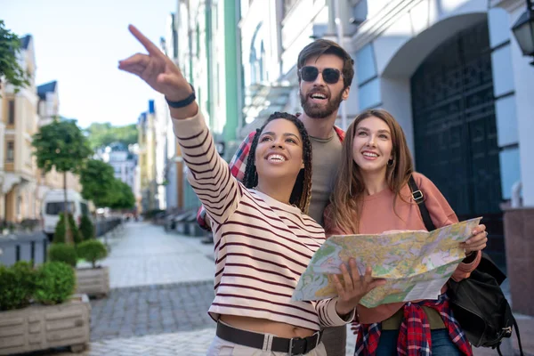 Two girls and guy standing on street looking interested — Stock Photo, Image