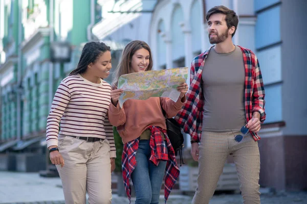 Sakallı adam ve haritalı kızlar caddede yürüyor. — Stok fotoğraf