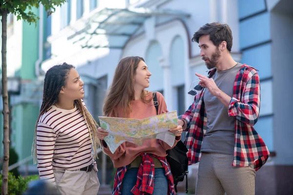 Guy holding zonnebril meisje met kaart een andere mulatto staan op straat — Stockfoto