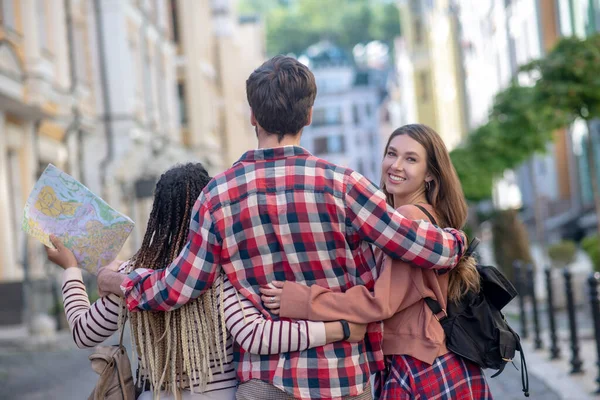 Guy in geruite shirt knuffelen twee meisjes vriendschappelijk — Stockfoto