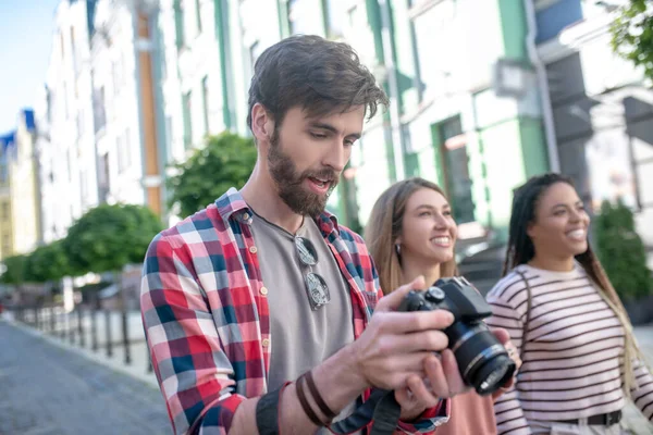 Сосредоточенный парень смотрит фотографии на камеру во время прогулки по городу — стоковое фото