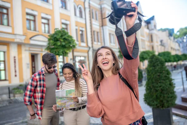 Счастливая девушка с камерой делает селфи друзей на расстоянии — стоковое фото