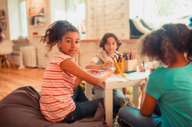Afrikalı-Amerikalı kız arkadaşlarıyla resim çiziyor.