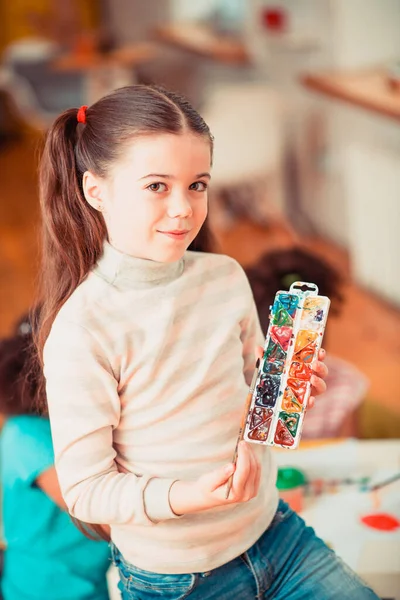 Young girl holding a brush and a palette of watercolors — Stock Photo, Image