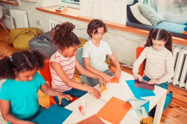 Crianças fazendo figuras de origami coloridas no grupo — Fotografia de Stock