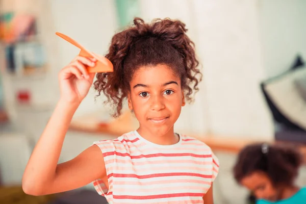 Маленька дівчинка робить оранжевий паперовий літак — стокове фото