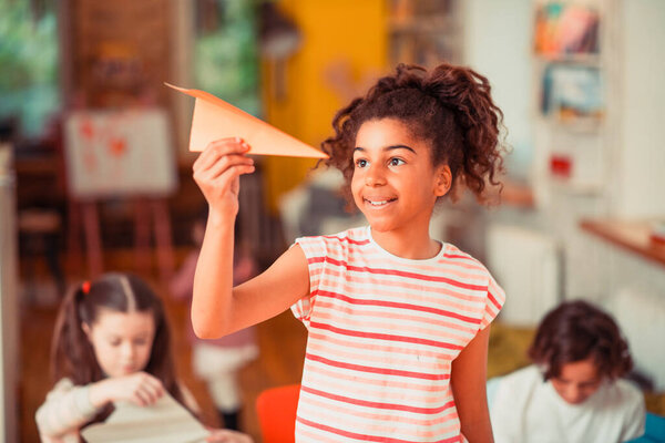 Smiling girl enjoying her origami paper plain